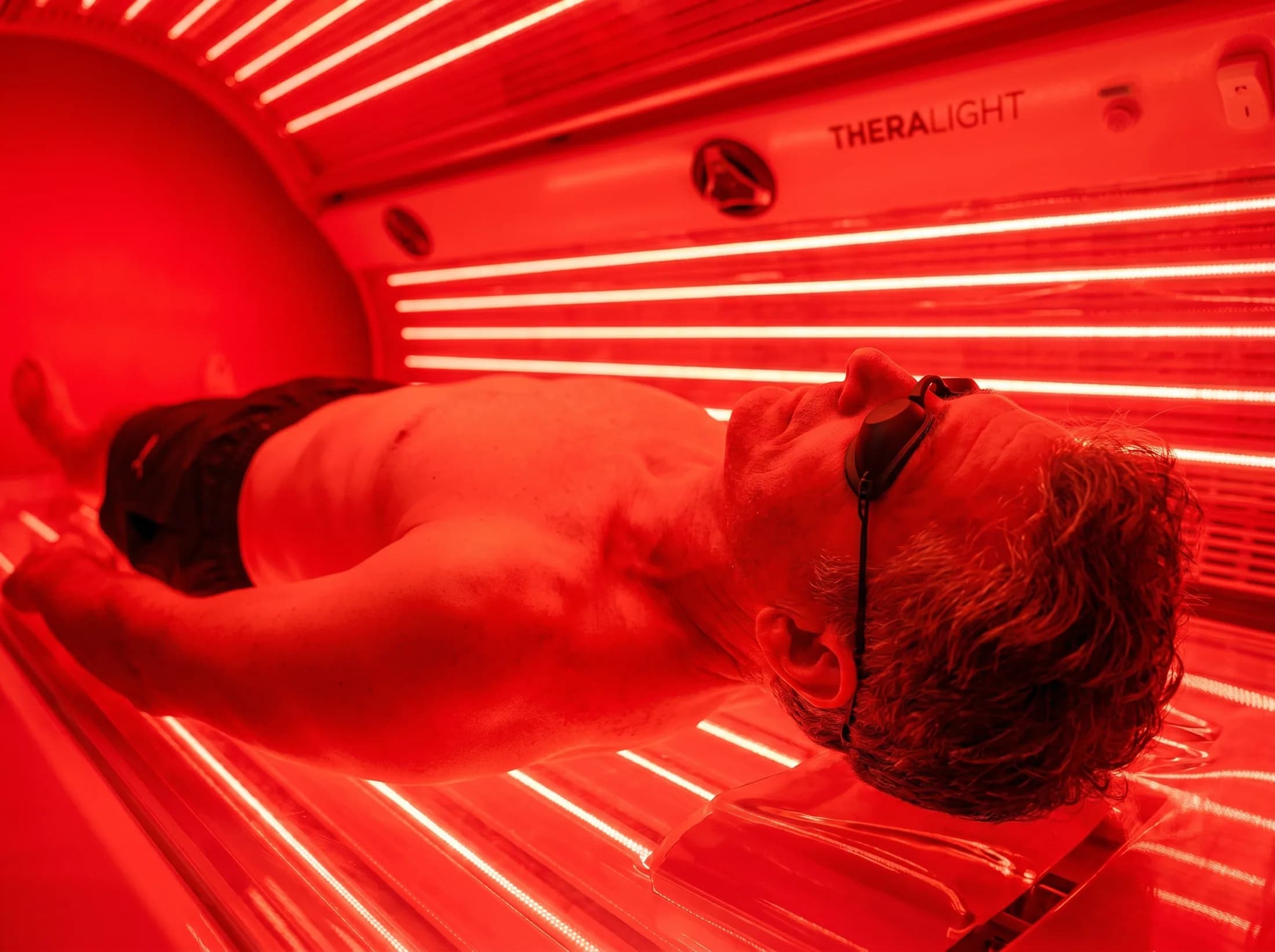 Side close-up of a man resting under red light panels