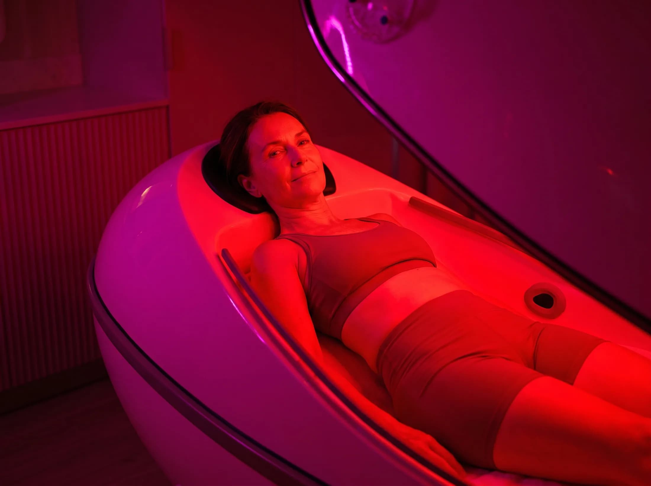 Woman reclining inside the infrared sauna cocoon from the side