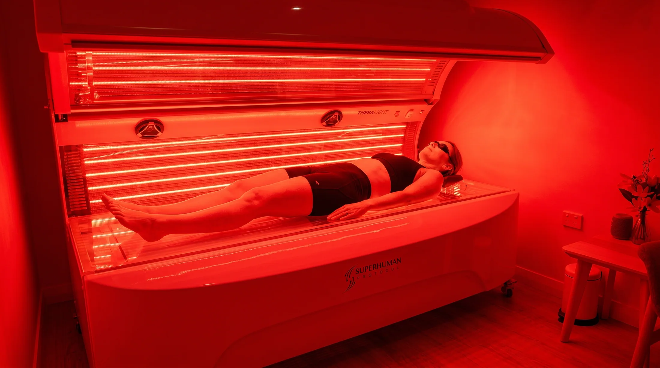Woman lying in a full-body red light therapy bed during a session